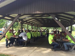 Austin construction team members wearing yellow safety shirts in pavillion during celebratory picnic lunch
