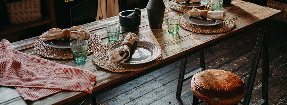 Table served for dinner. Cozy kitchen interior. Cultery and napkins on table for guests. Family breakfast. Dining time. No people.
